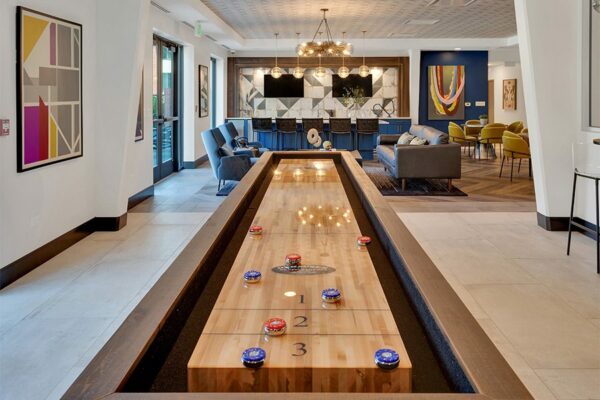 Detail of shuffleboard table in game room with tiled floor and wall art.