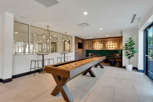 Game room with shuffleboard table, bar tables with stools, and lounge with booths and TV.