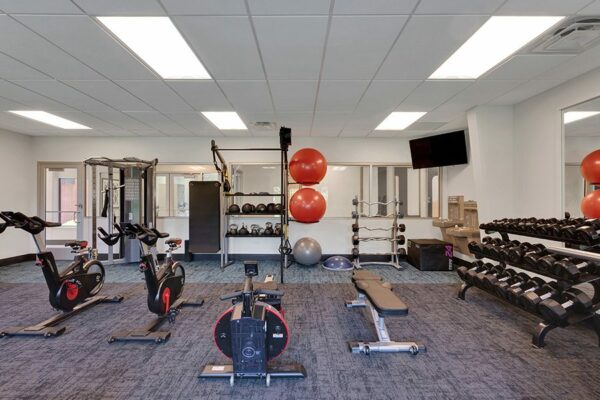 Fitness center with wall mounted TV and weightlifting and cardio equipment.