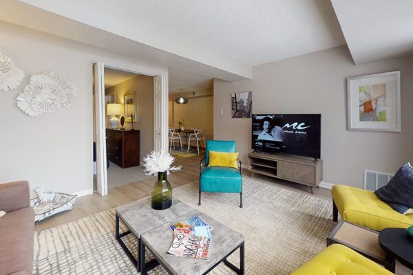 Living room with plush seating, modern furniture, large TV, and doors to bedroom and dining room.
