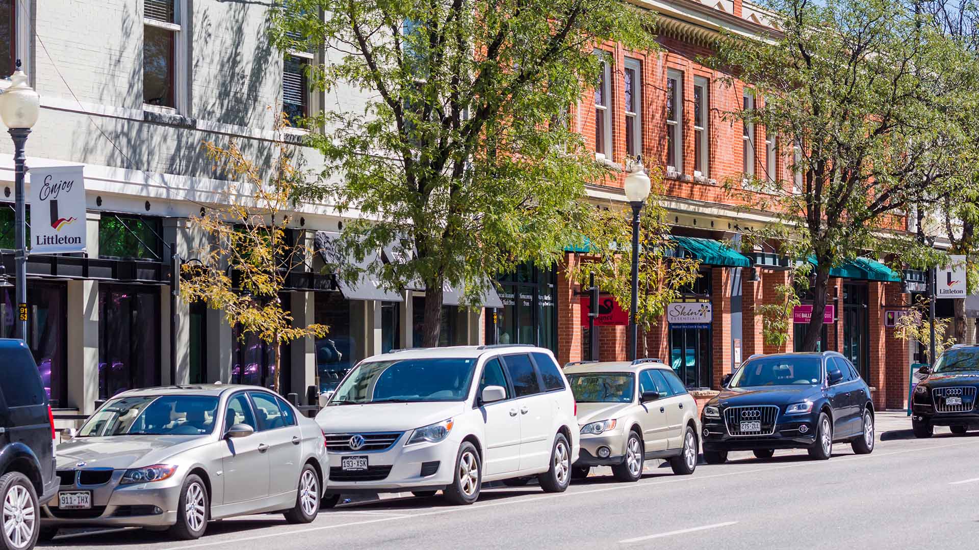 Littleton Boulevard through downtown Littleton lined with vintage shops, tall trees, and parked cars.