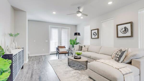 Living room with wood floor, rug, plush sectional, modern furniture, and door to balcony.