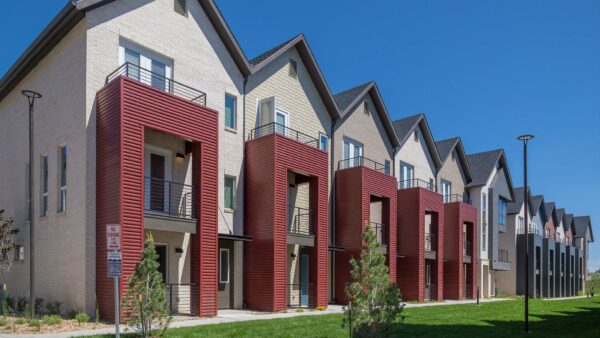 Dayton Station townhomes with red metal siding and balconies overlooking lush lawn.