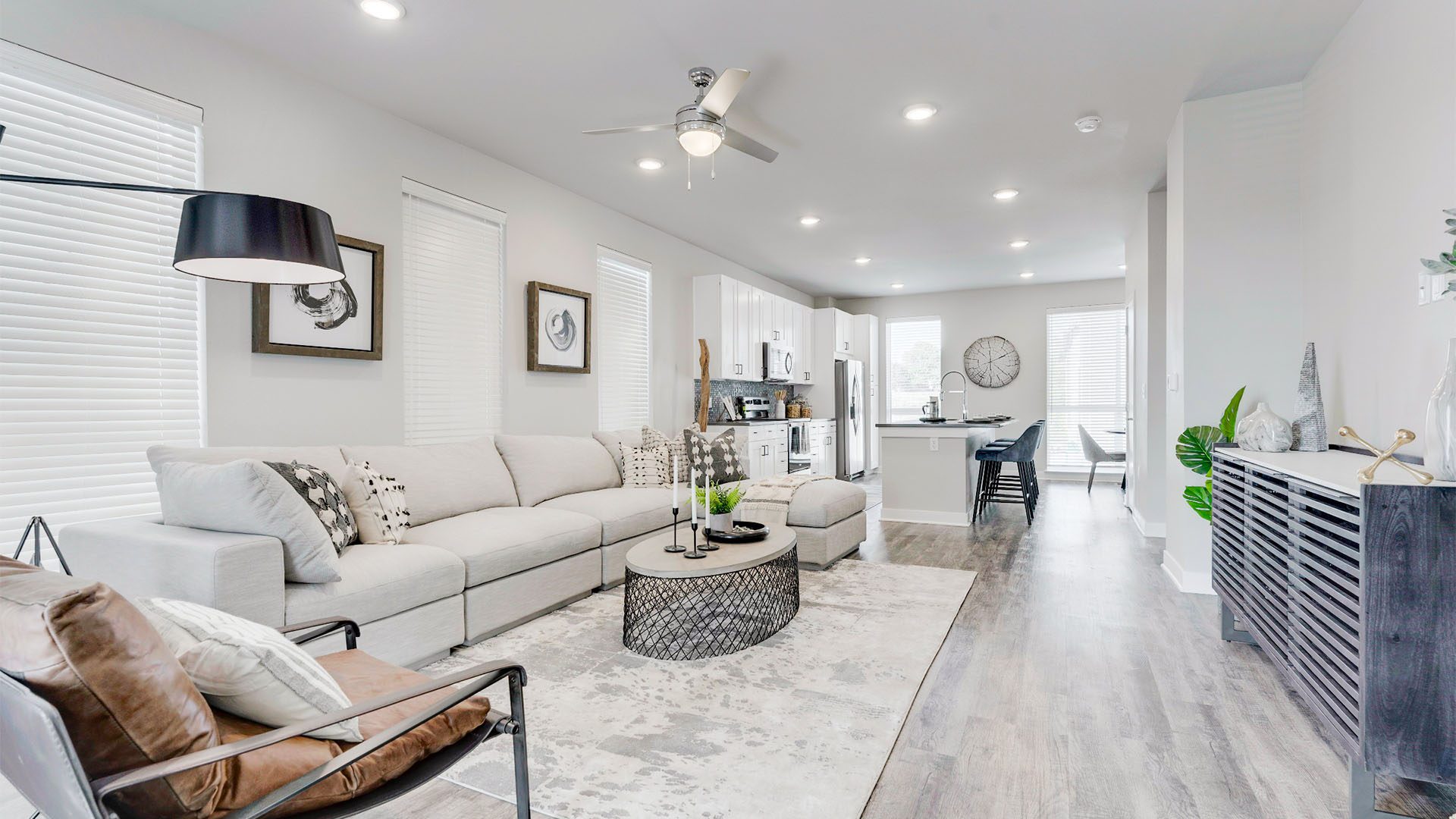 Living room with wood floor, modern furniture, plush sectional, and leather lounge chair.