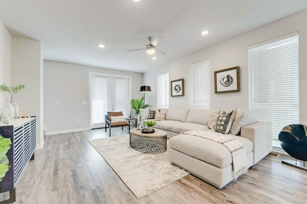 Living room with wood floor, plush sectional couch, modern furniture, and large windows.
