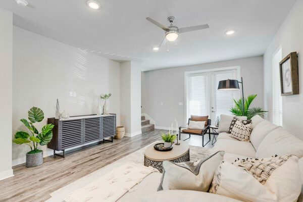 Living room with wood floor, plush sectional couch, modern furniture, and large windows.