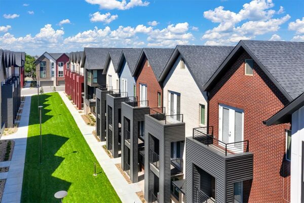 Aerial view of Dayton Station townhomes with red siding and balconies overlooking lush lawn.