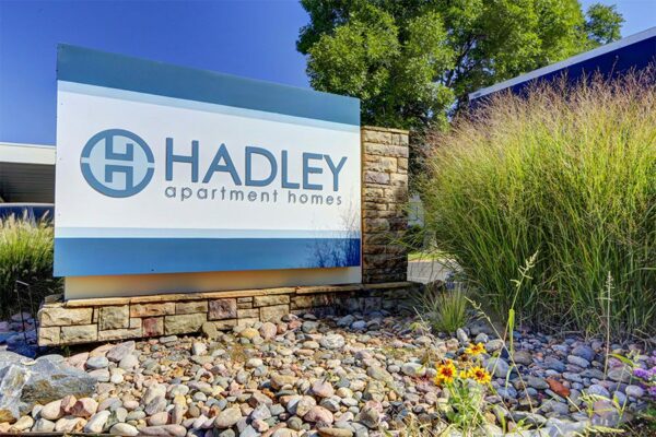 Lush landscaping surrounding monument sign for Hadley apartments.