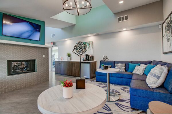 Lounge with plush sectional, bar tables, fireplace, wall mounted TV, and skylight.