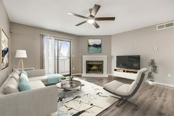 Living room with wood floor, modern furniture, ceiling fan, fireplace, and door to balcony.