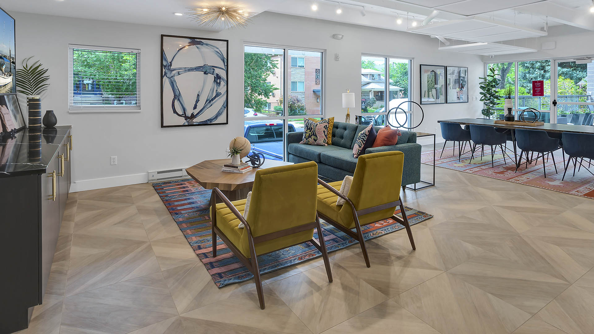 Lounge with wood floor, plush seating, eclectic modern decor, and large windows.