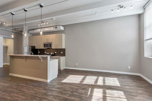 Living area with wood floor, grey walls, high ceilings, and kitchen with island.