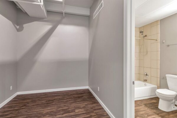 Apartment living area with wood floor, grey walls, and door to bathroom.