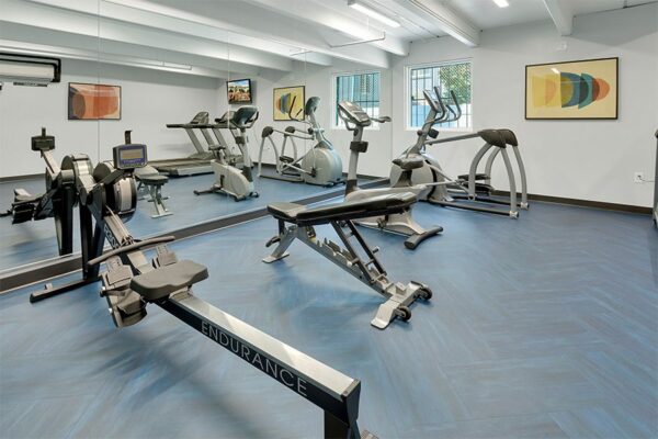 Fitness center with mirror wall, elliptical, exercise bike, and rower.