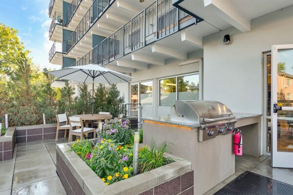 Patio with lush planters, dining table with umbrella, and built in BBQ grill.