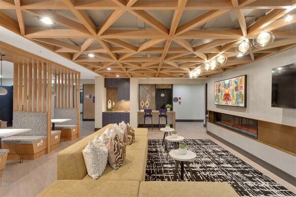 Lounge with wide modern fireplace, wall mounted TV, large sectional, booths, and artwork.