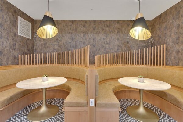 Lounge with large round booths with stone tables and decorative lights.