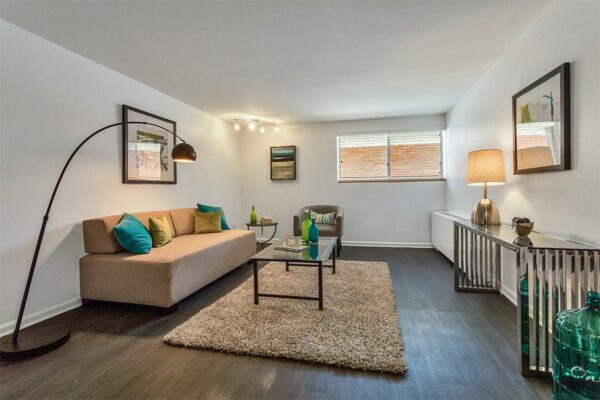 Living room with wood floor, plush rug, modern furniture, floor standing lamp, and large window.