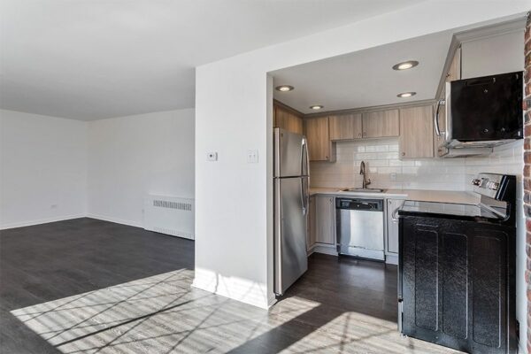 Kitchen with wood floor, light cabinets and counters, and stainless steel appliances.