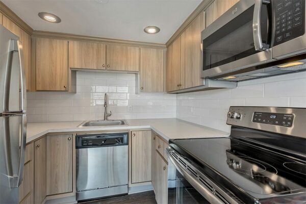 Kitchen with light cabinets and counters, stainless steel appliances, and subway tiled backsplash.