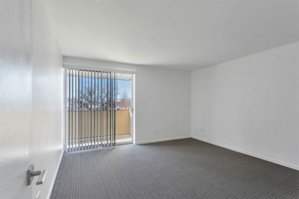 Bedroom with carpet and sliding door to balcony.