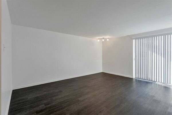 Living room with wood floor, cool grey walls, lighting fixture, and sliding door to balcony.