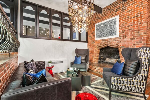 Lounge with brick fireplace, wingback chairs, leather couch, and eclectic decor.