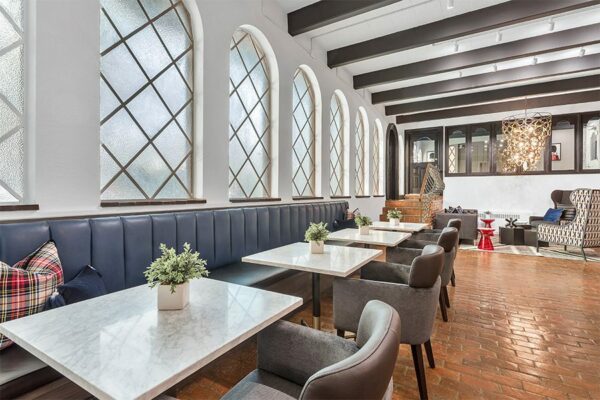 Lounge with tiled floor, plush booth seating with tables, and classical interior design.