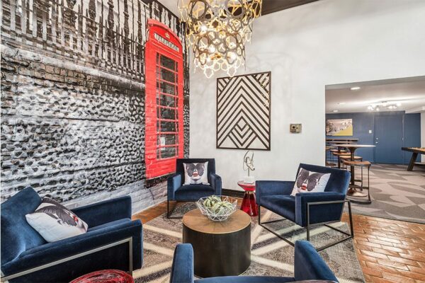 Lounge with modern blue velvet chairs, pop art wallpaper with phone booth, and eclectic decor.