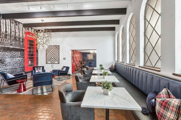 Lounge area with tiled floor, plush booth seating with tables, modern blue velvet lounge chairs, and classic styling.