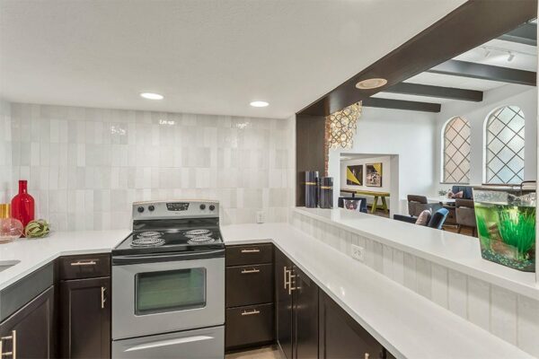 Community kitchen with wood cabinets, tiled walls, stainless steel appliances, and breakfast bar.