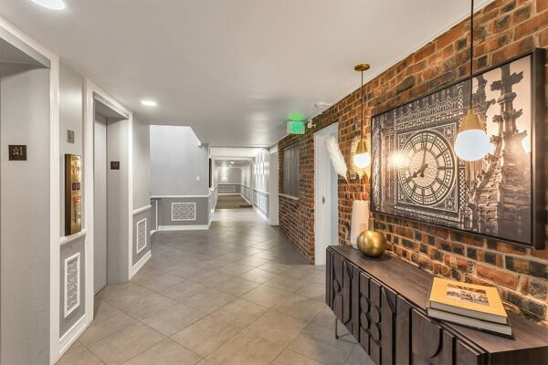 Hallway with tiled floor, brick accent wall, brass pendant lights, and eclectic decor.