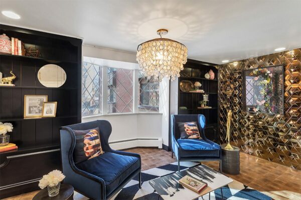 Lounge with end grain wood floor, built in shelves, geometric metal accent wall, and eclectic decor.