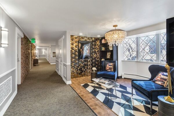 Lounge with end grain wood floor, built in shelves, geometric metal accent wall, and eclectic decor.