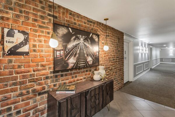 Hallway with carpet, brick accent wall, brass pendant lights, and eclectic decor.