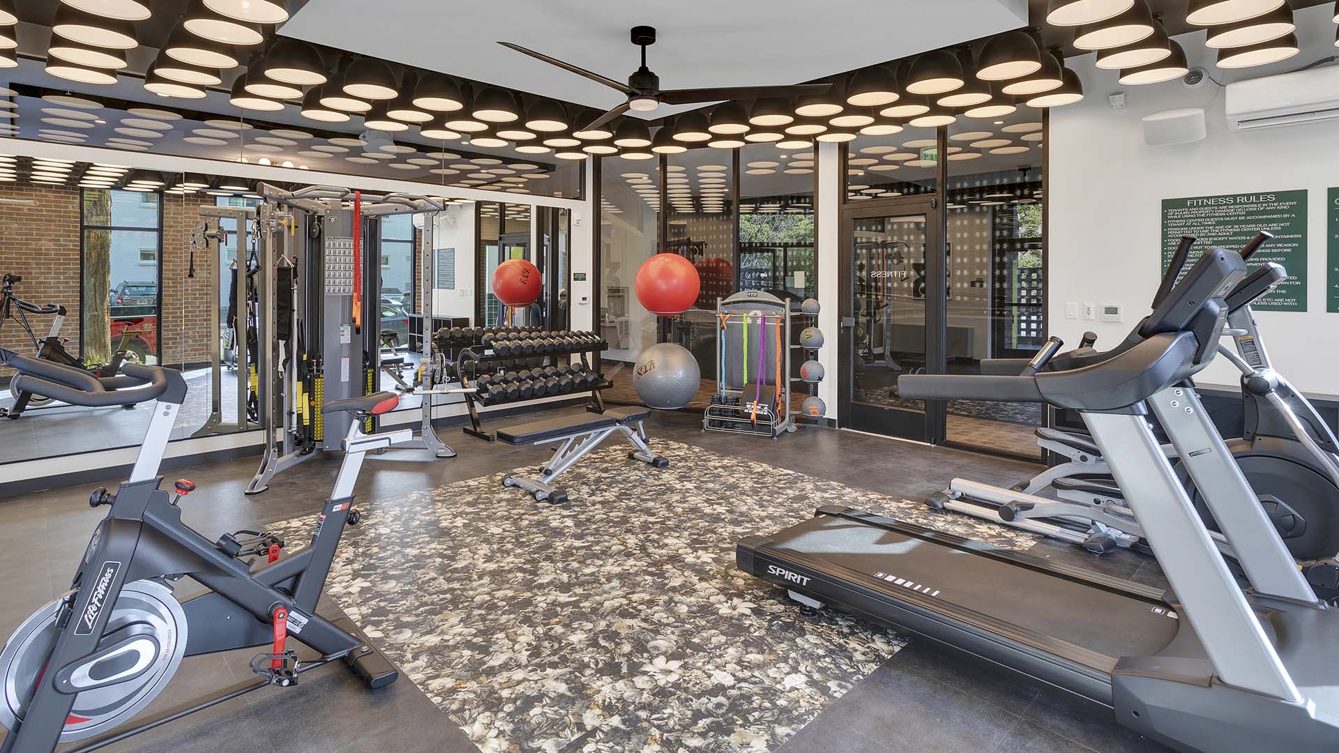 Fitness center with cardio machines, weight equipment, mirror walls, and decorative lights.