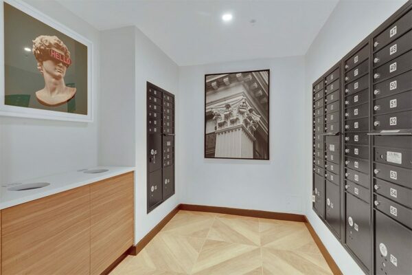 Mail room with large tiled floors, mailboxes, and framed artwork.