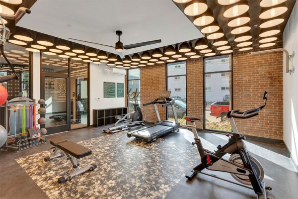 Fitness center with storage cubbies, cardio equipment, and large ceiling fan.