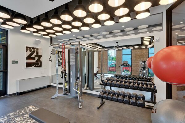 Fitness center with mirror wall, weight equipment, and exercise balls.