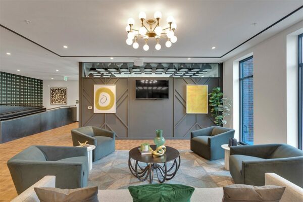 Lounge with modern light fixture, comfortable plush furniture, artwork, and large windows.