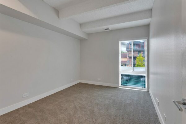Bedroom with carpet, grey walls, white trim, and large window.
