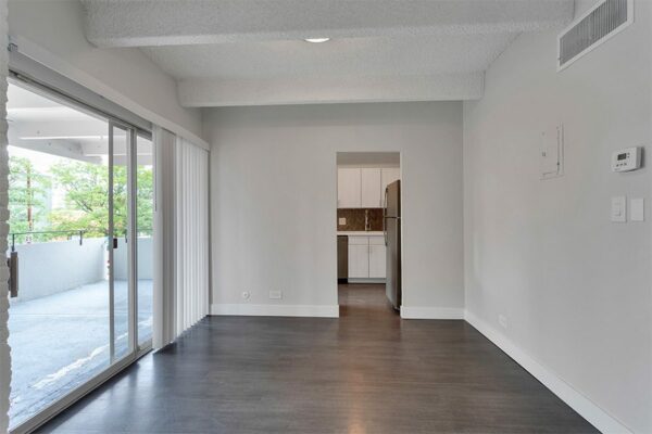 Living room with wood floor, grey walls, white trim, and doors to balcony and kitchen.
