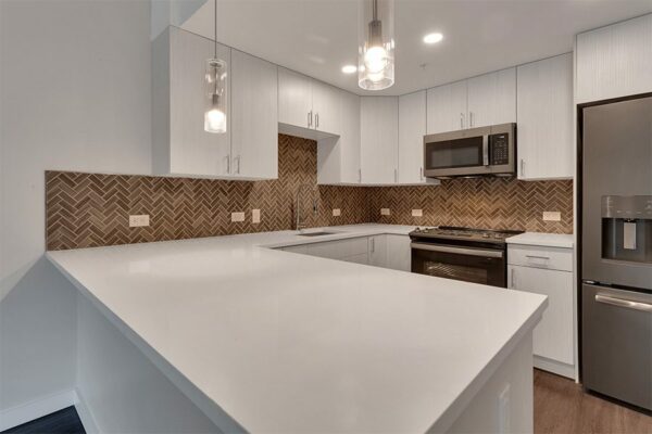 Kitchen with light cabinets and counters, stainless steel appliances, and breakfast bar with pendant lights.