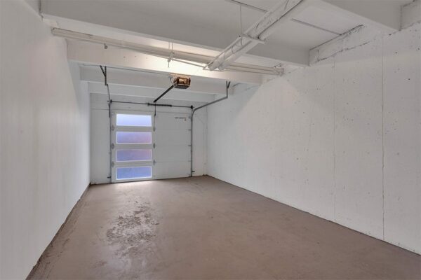 Garage with concrete floor and walls and overhead door.