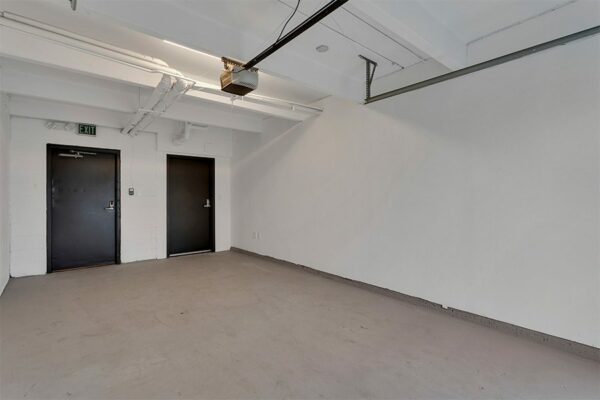 Garage with concrete floor and walls and doors to units.