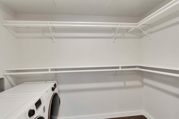 Closet with built in shelves and washer dryer.