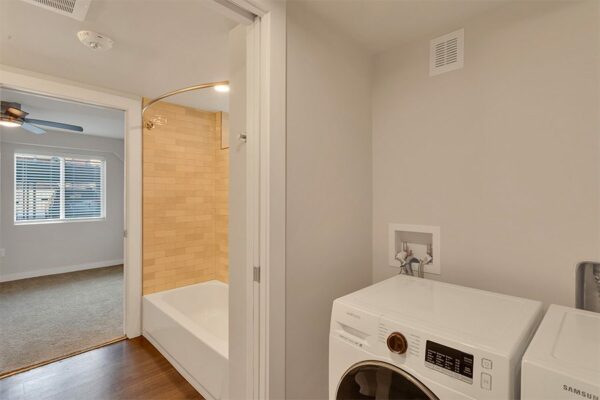 Closet with washer and dryer and door to bathroom with tiled shower tub.