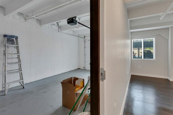 Living space with wood floor and large windows and door to attached garage.