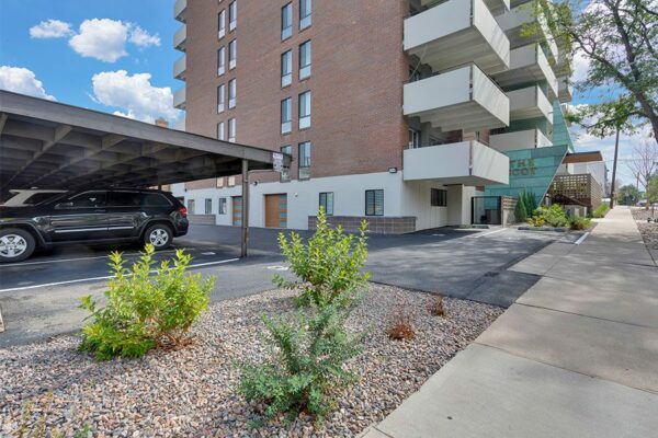 The Scot apartment building with large balconies, rocky landscaping, and covered parking.