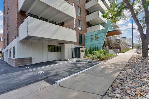 The Scot apartment building with numbered parking, large balconies, and mature trees.